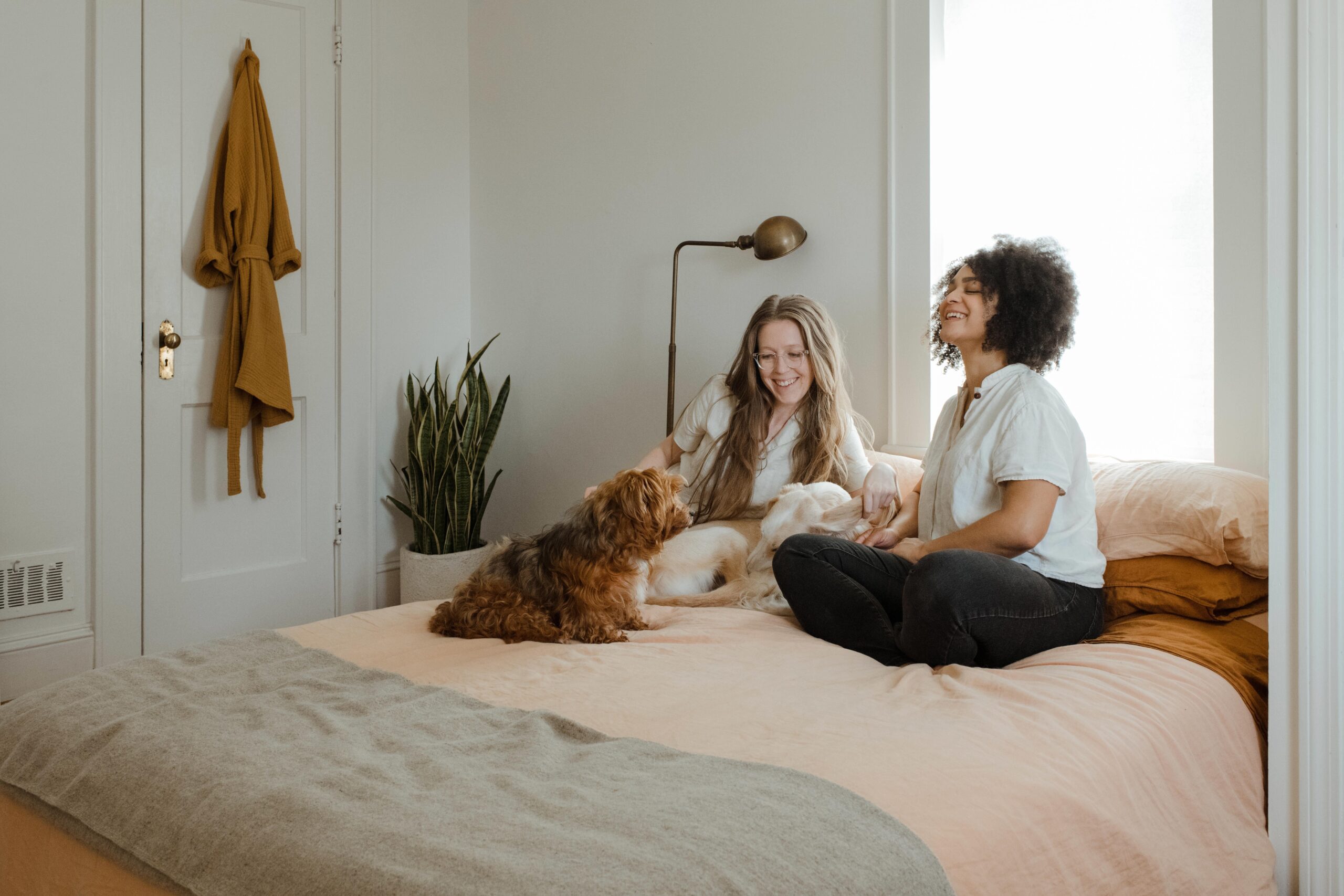 Two women sitting on bed with dog